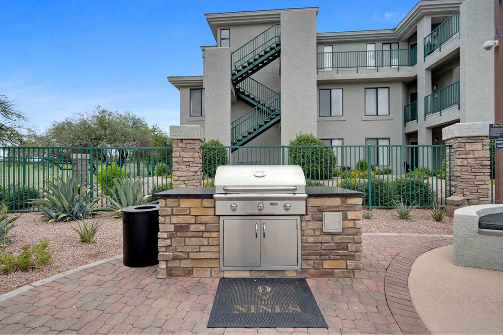 A brick BBQ grill is in front of a stone pillar with a sign that says