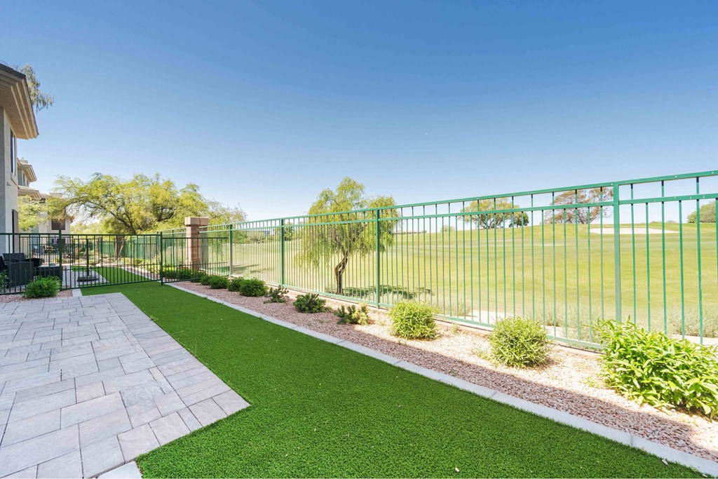 A green fence surrounds a green lawn.