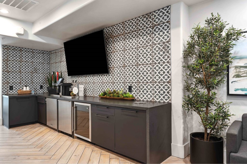 A modern kitchen with a black and white tiled backsplash and dark wood flooring.