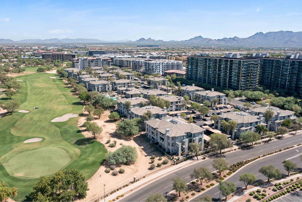 A golf course is surrounded by apartment buildings.