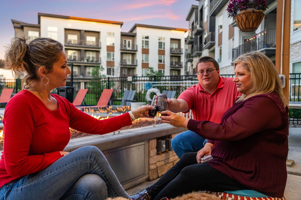 Two women and a man are sitting at a table, playing a game with cards.