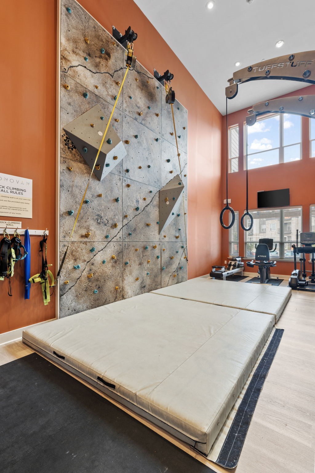 a climbing wall and mattress in a room with other equipment