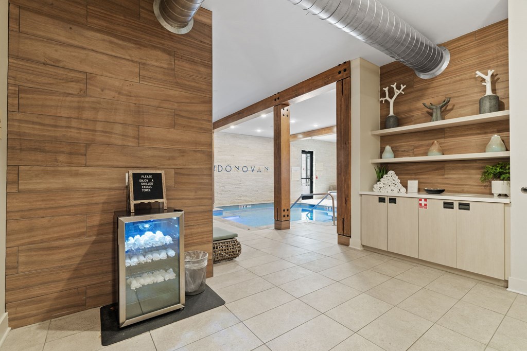 A room with a wooden wall and a pool in the background.