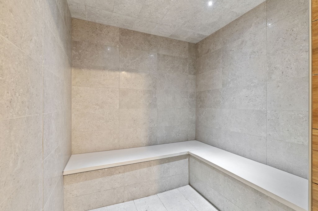 A corner of a room with a bench and tiled walls.