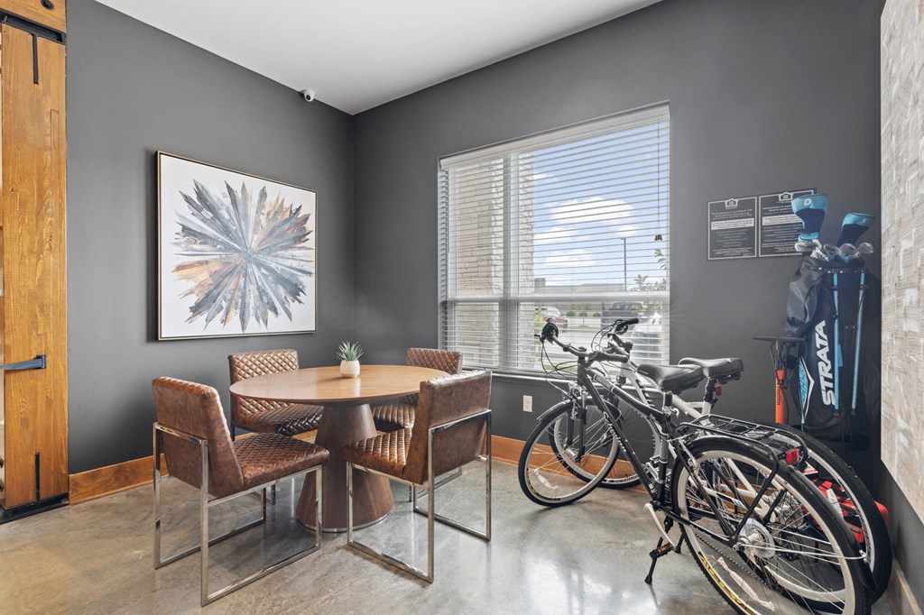 A room with a dining table and chairs and a bicycle.