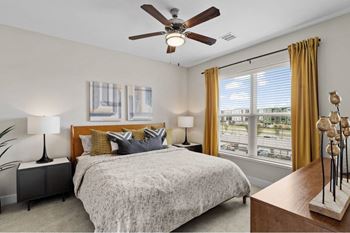 a bedroom with a large window and a ceiling fan