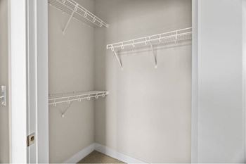 a walk in closet with a white wall and hanging racks