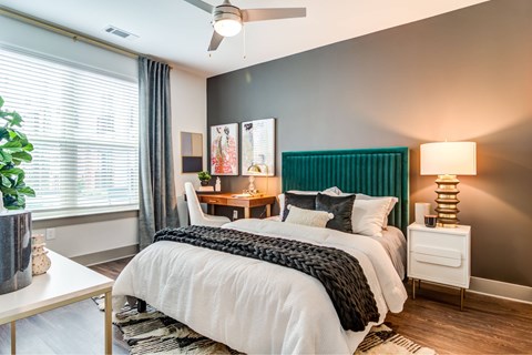 A bedroom with a white bed and a white nightstand with a lamp.