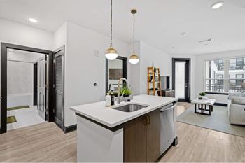 an open kitchen and living room with white walls and wood floors