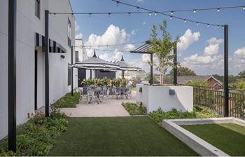 a patio with tables and chairs and a lawn