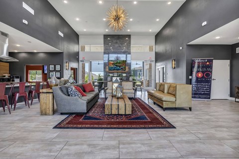 A spacious living room with a grey sofa set and a red rug.
