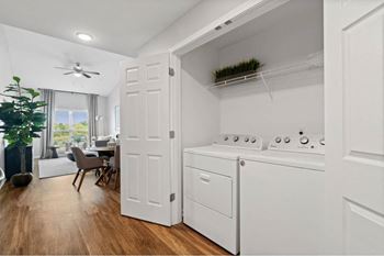 an open kitchen with a washer and dryer and a living room with a