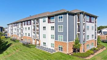 A large apartment complex with a grassy area in front.
