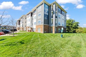 an apartment building with a green lawn in front of it