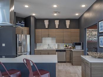 A modern kitchen with a refrigerator, sink, and bar stools.