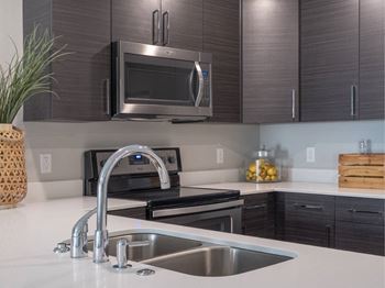 A modern kitchen with a stainless steel sink and microwave.