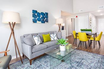 A living room with a grey couch, yellow chairs, and a blue patterned rug.