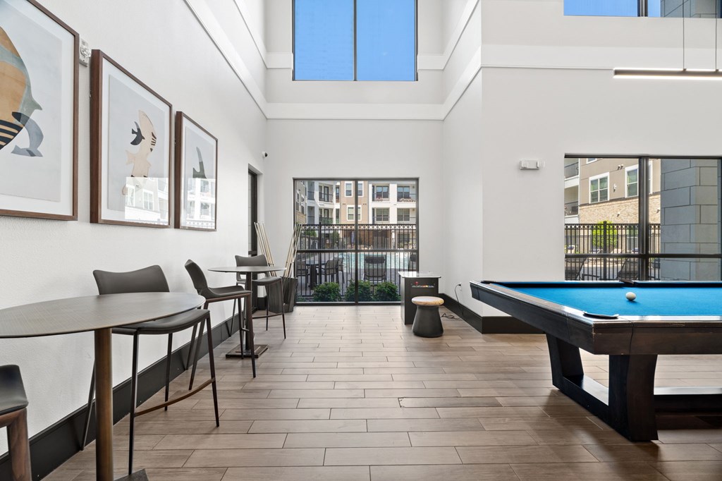 A room with a pool table and a view of the city.