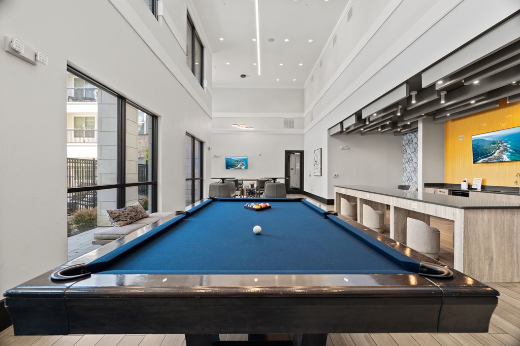 A pool table in a room with a bar area.