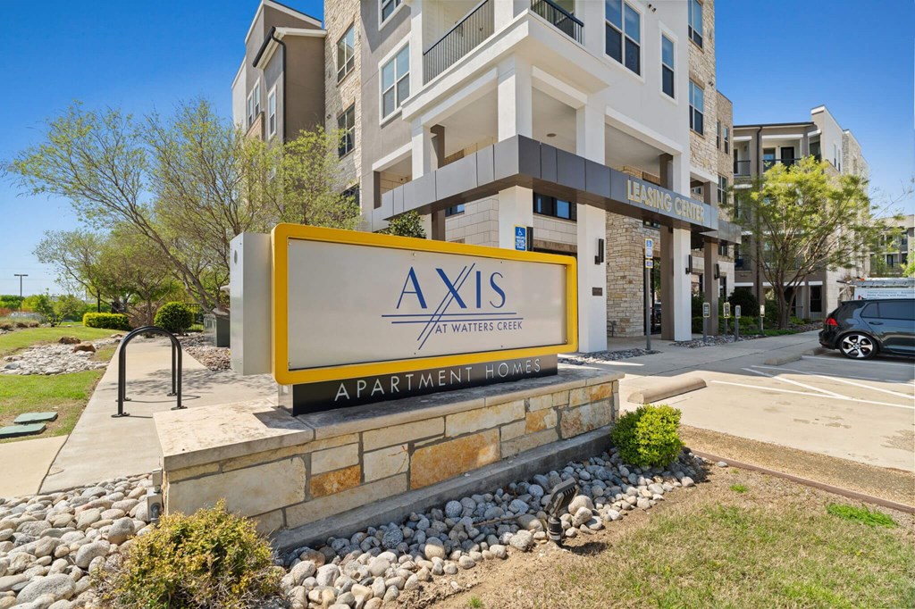 A sign for Axis Apartments in front of a building.