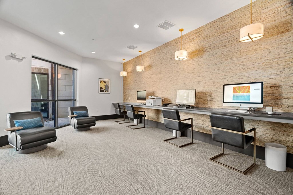 A modern office space with a brick wall and a long desk with chairs.