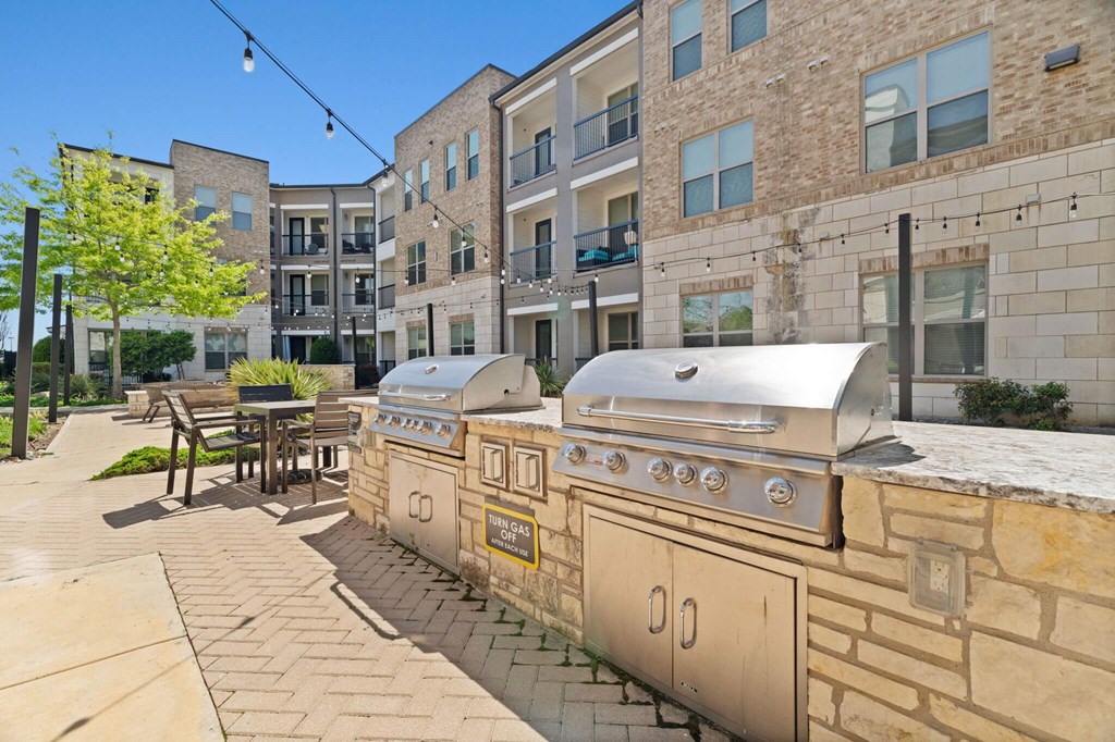 A row of outdoor BBQs are lined up on a patio.