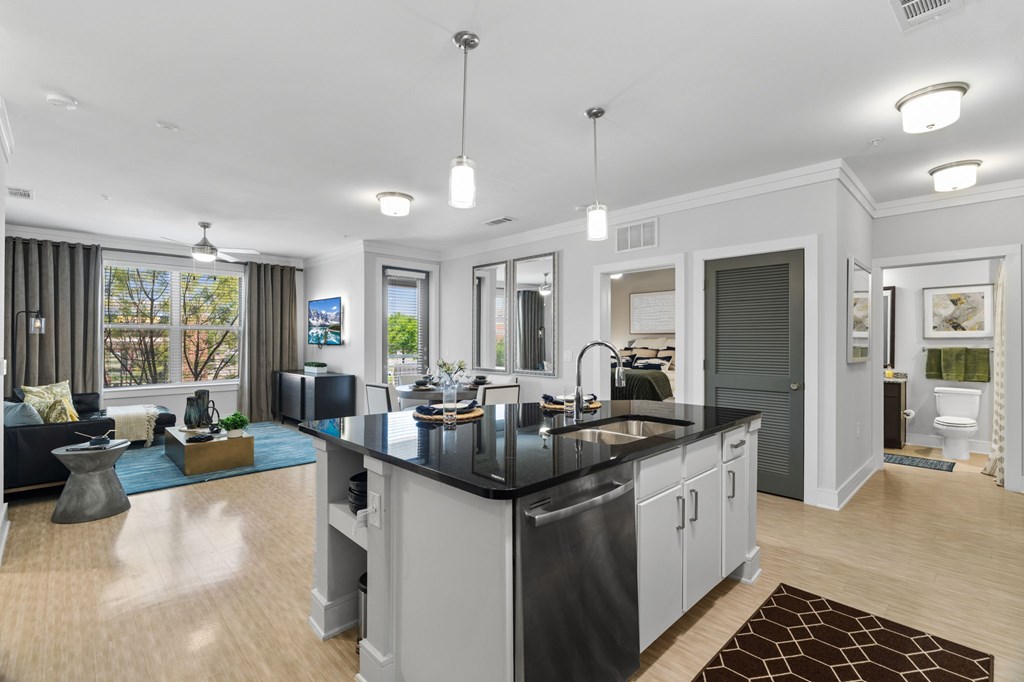 A modern kitchen with a black countertop and stainless steel appliances.