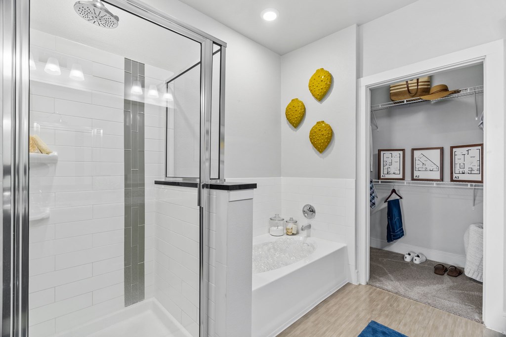 A bathroom with a glass shower door and a white tub.