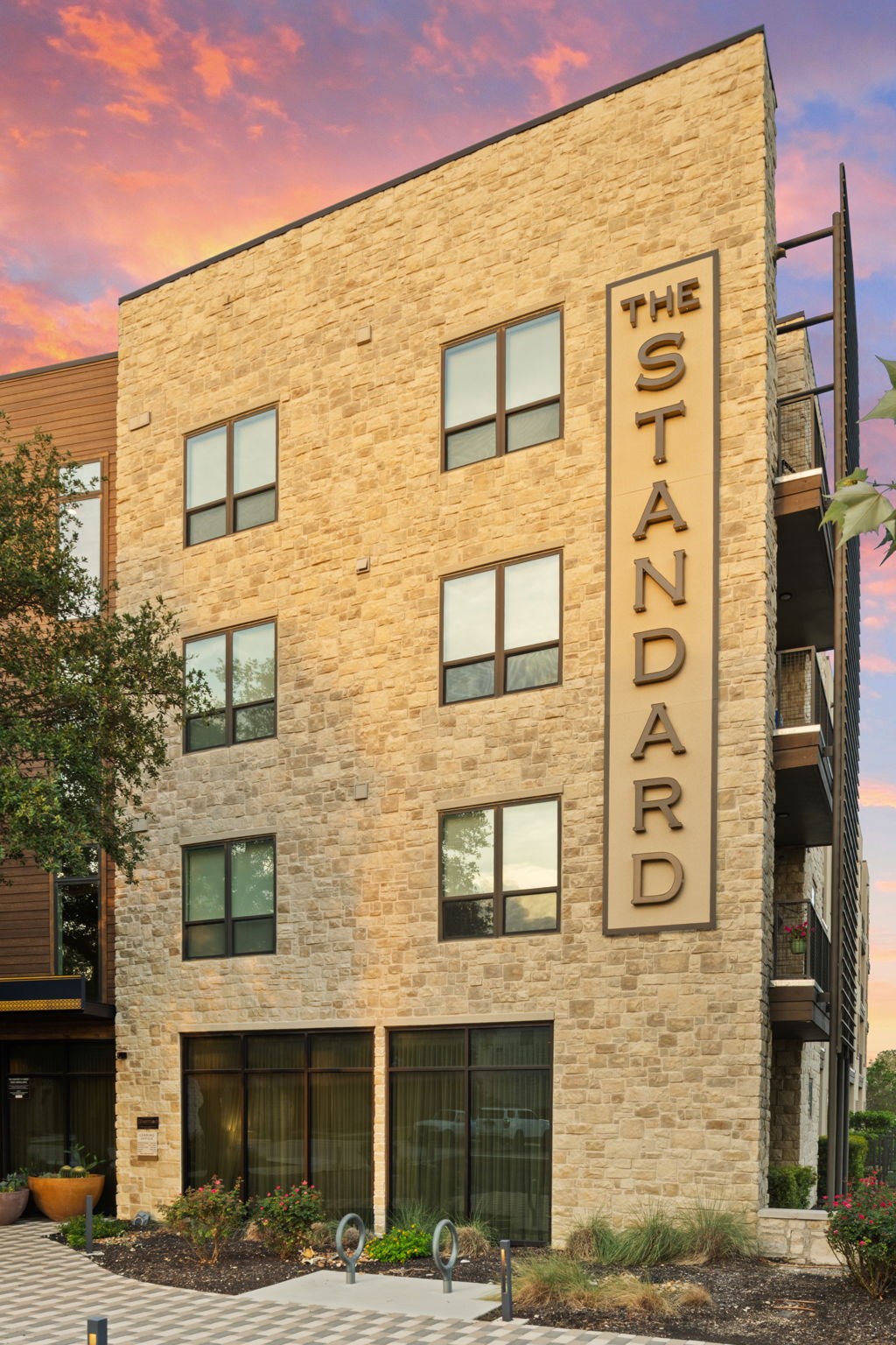 The Standard building has a brick facade and is surrounded by a landscaped area.