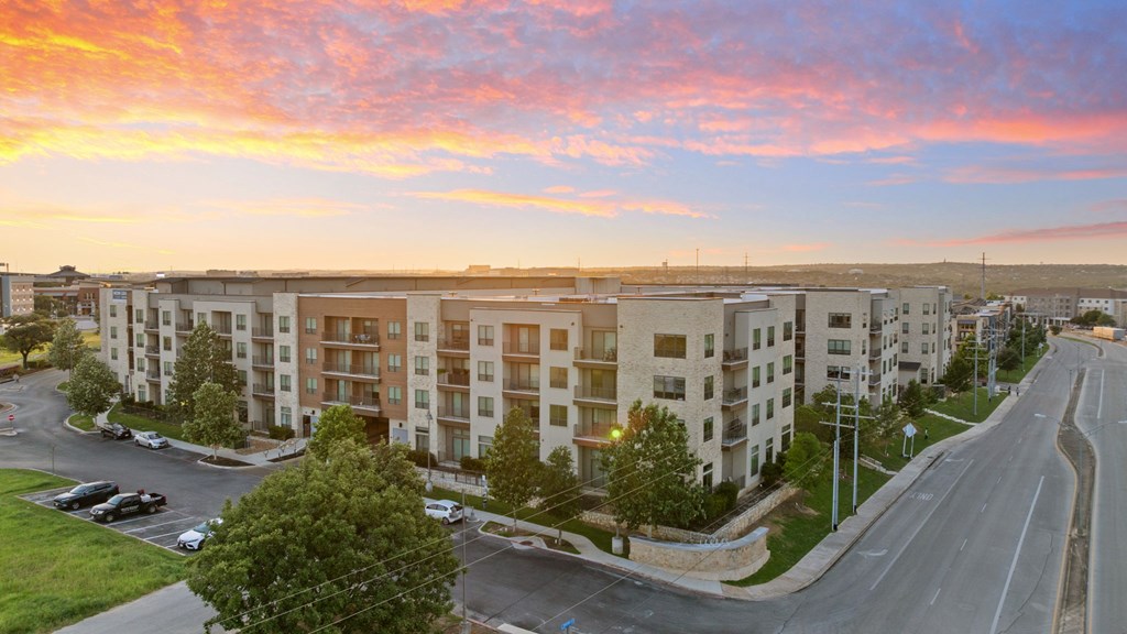 A sunset view of a street with apartment buildings on the side.