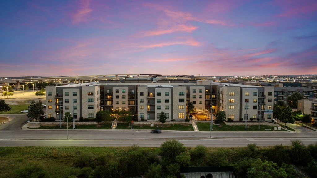 A large apartment complex is shown with a beautiful sunset in the background.