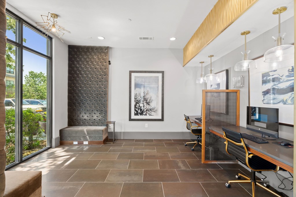 A room with a desk and chairs with a painting hanging on the wall.