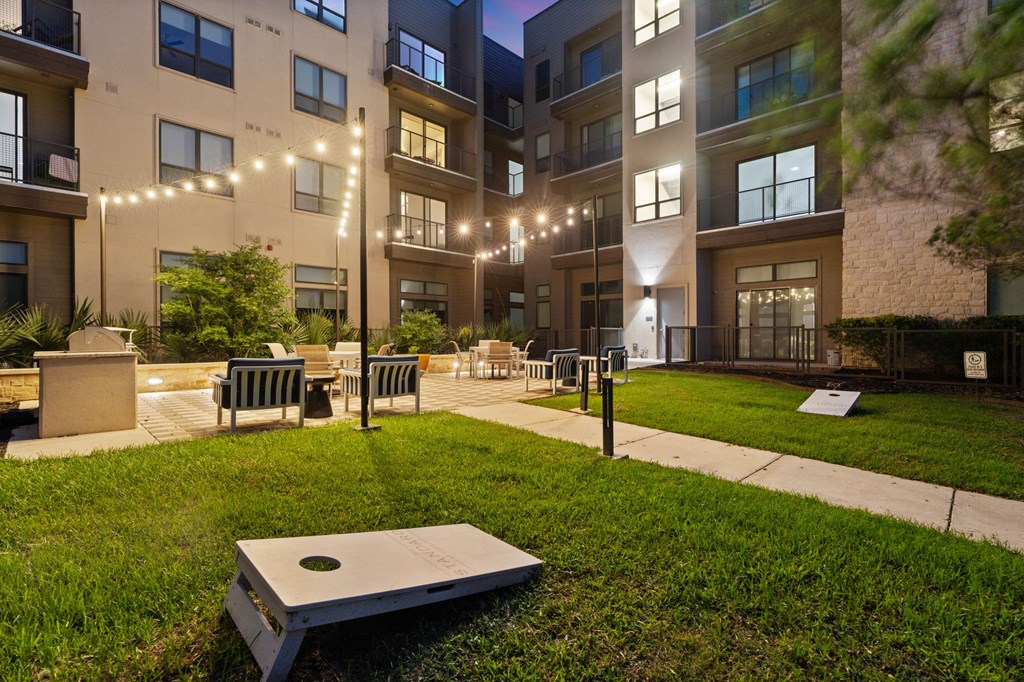A modern apartment complex with a grassy courtyard and benches.