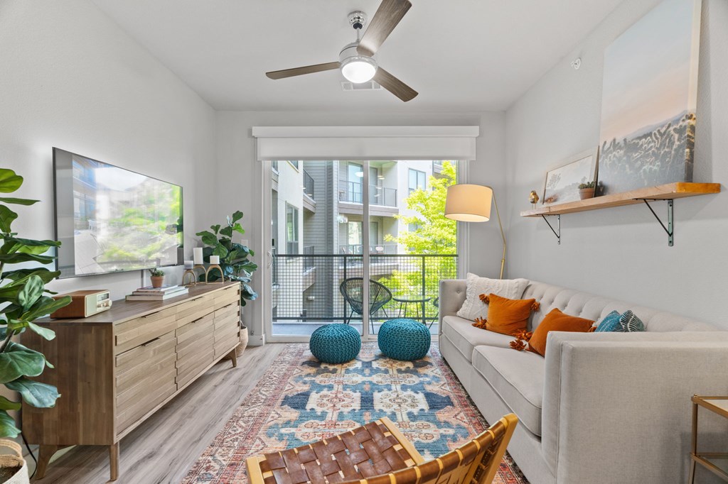 A living room with a white couch, a wooden dresser, a ceiling fan, and a rug.