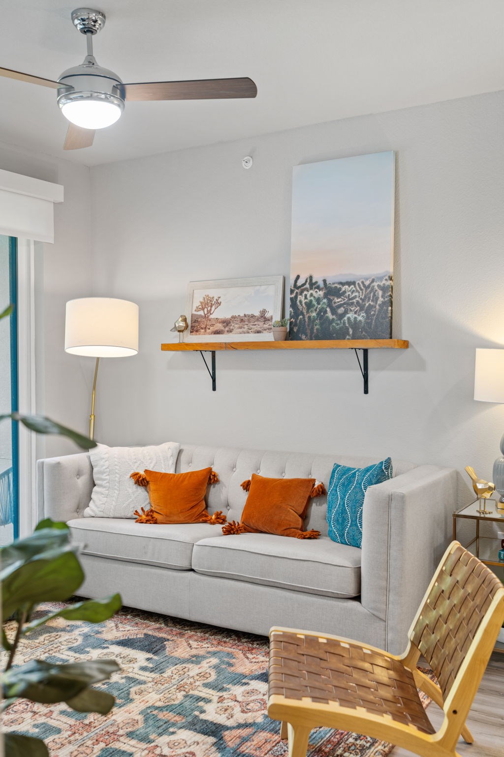 A living room with a white couch, a wooden chair, and a ceiling fan.