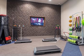 A gym with a television on the wall and various exercise equipment.