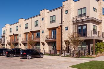 A black car is parked in a parking lot in front of a building.