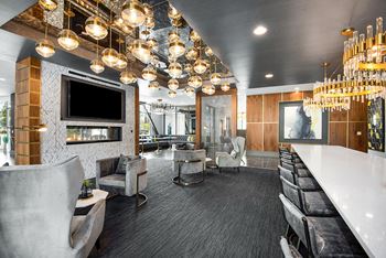 A modern lounge area with a long white table and black chairs.