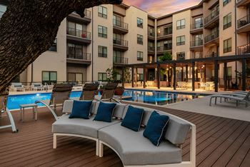 A poolside lounge area with a row of chairs and a couch.