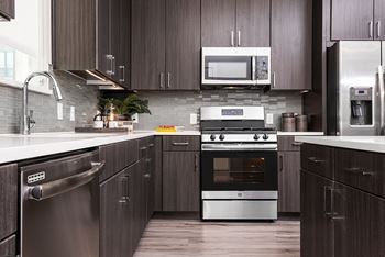 A modern kitchen with dark wood cabinets and stainless steel appliances.