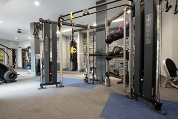 A gym with a variety of equipment including a squat rack, a leg press machine, and a bench press.