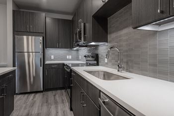 A modern kitchen with dark wood cabinets and stainless steel appliances.