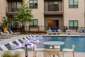 A pool with a table and chairs in front of a building.