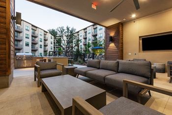 A modern living room with a large grey sofa and a television.
