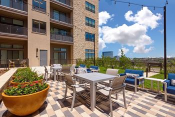 A patio with a table and chairs is surrounded by apartment buildings.