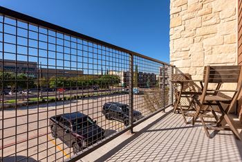 A black car is parked behind a metal fence on a sunny day.