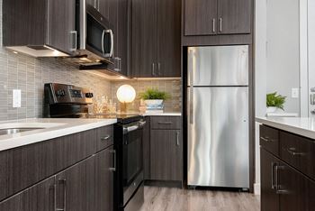 A modern kitchen with dark wood cabinets and stainless steel appliances.