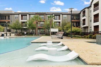 A swimming pool with a slide in front of apartment buildings.