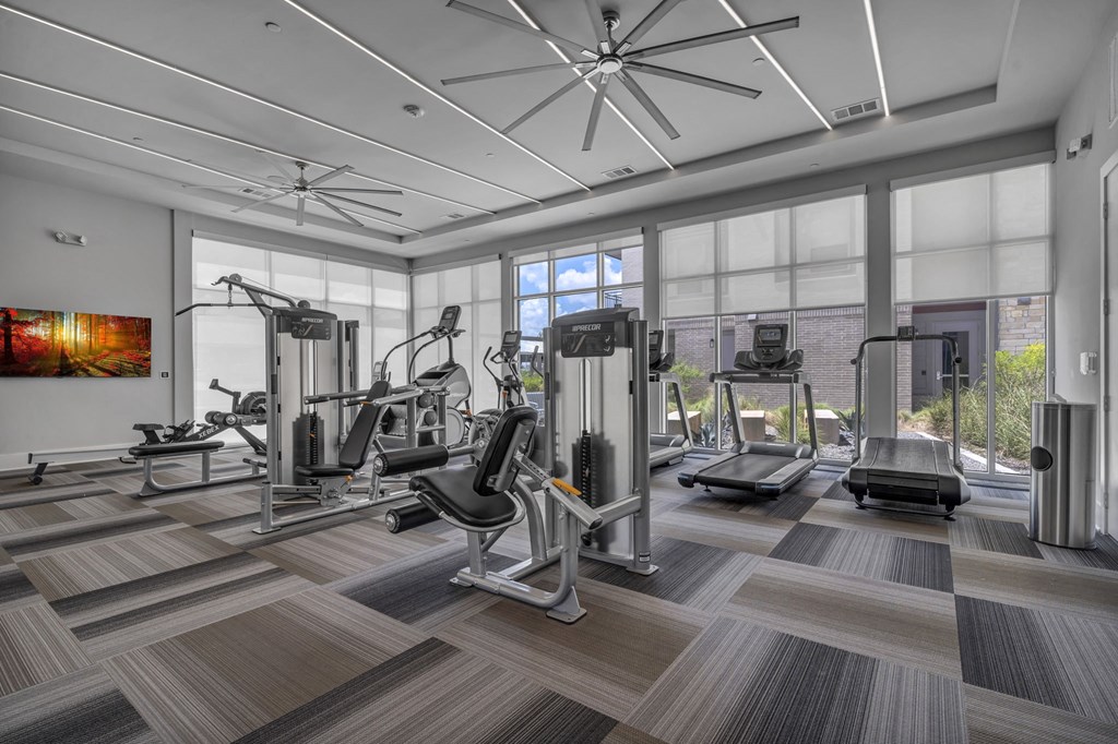 A spacious gym with a variety of equipment and a ceiling fan.