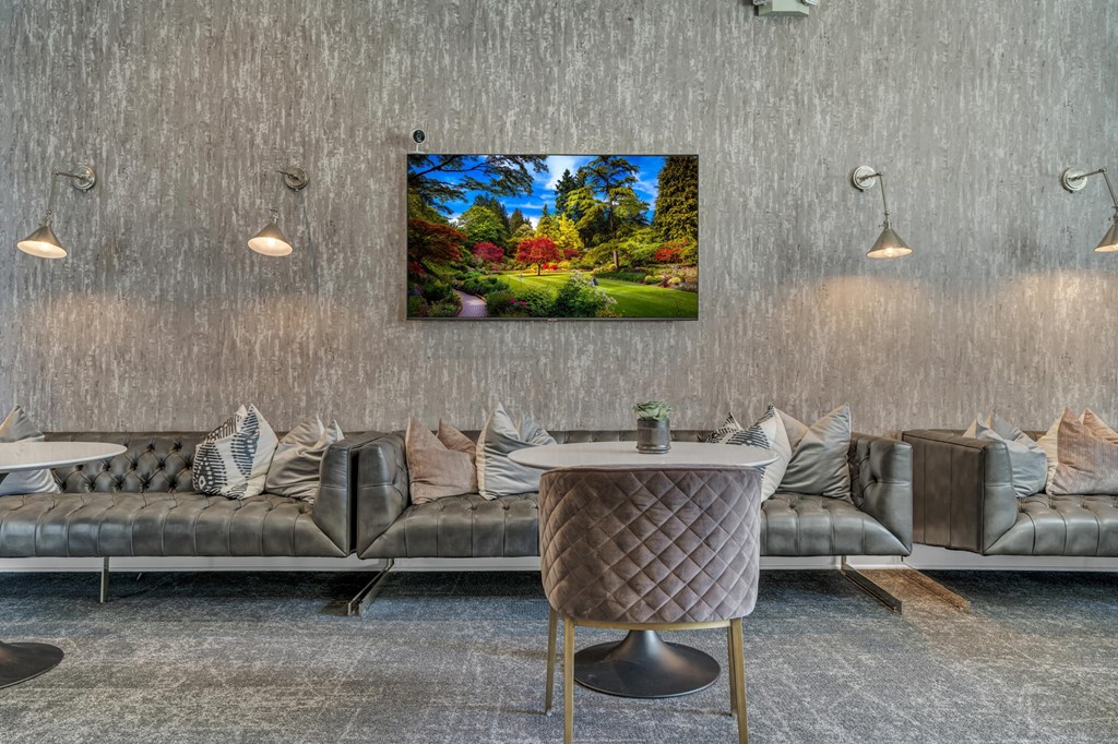 A modern living room with grey sofas and a large TV displaying a garden scene.